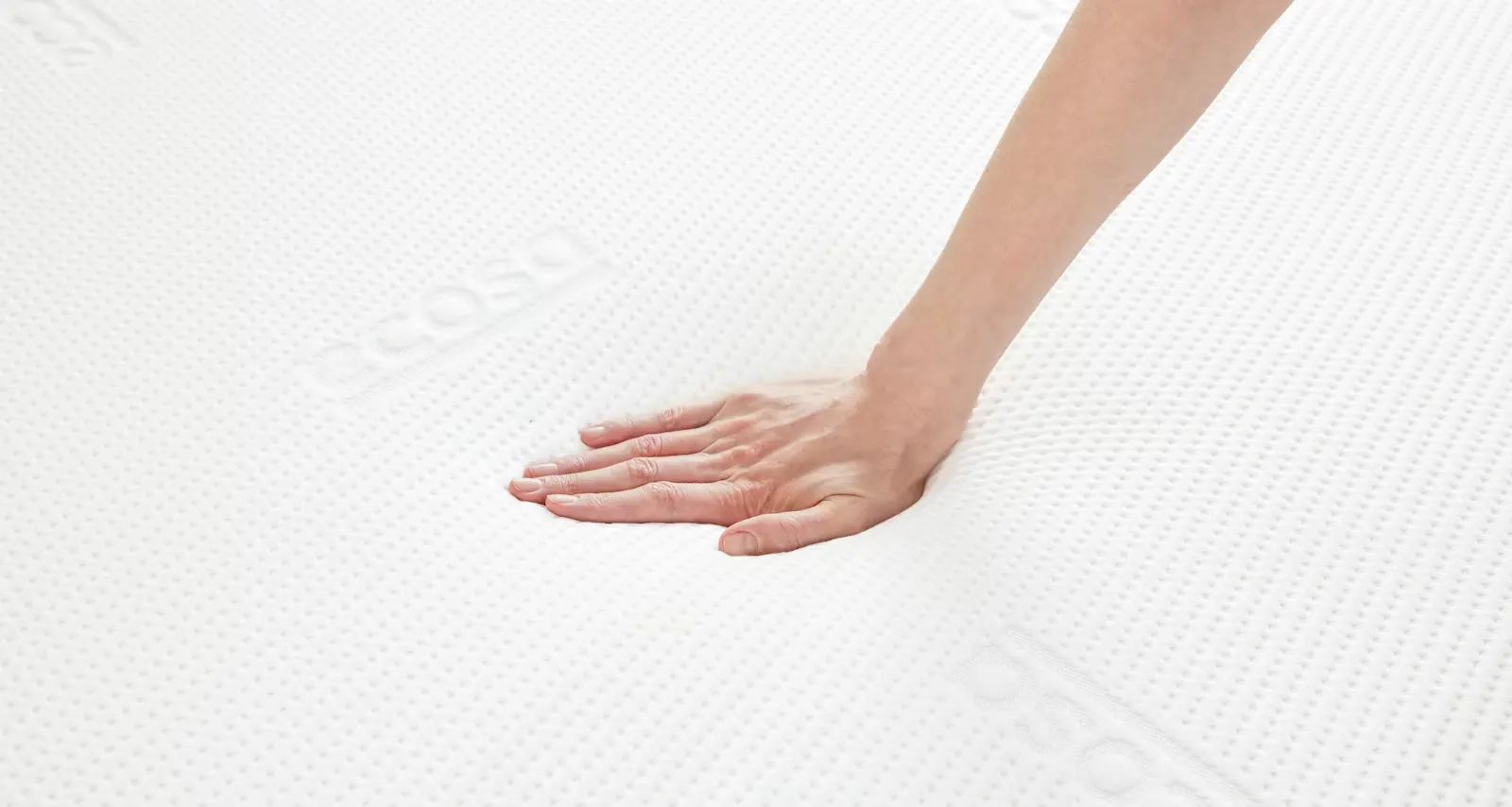 A hand pressing into the Ecosa mattress cover, showing how far the surface sinks under light pressure.