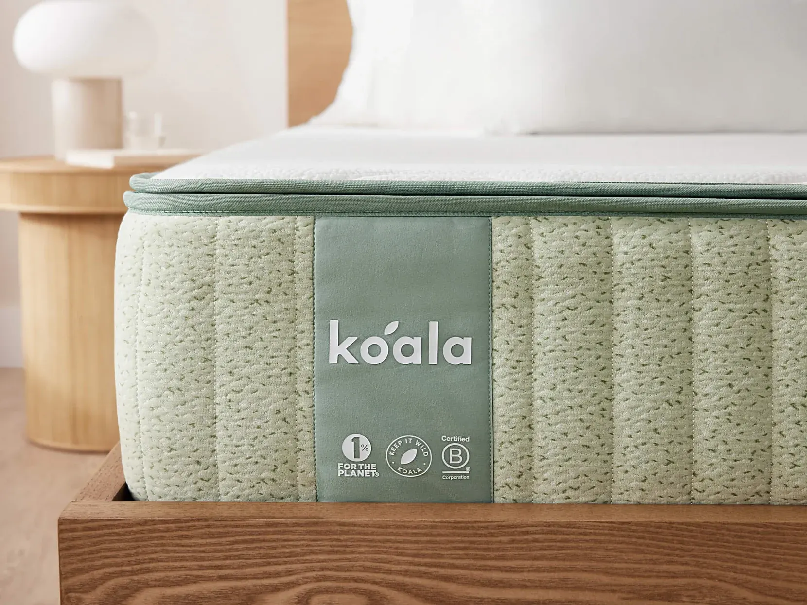 Close-up of the Koala mattress corner, showing the quilted sage-green side panel, the koala wordmark and the white top surface.