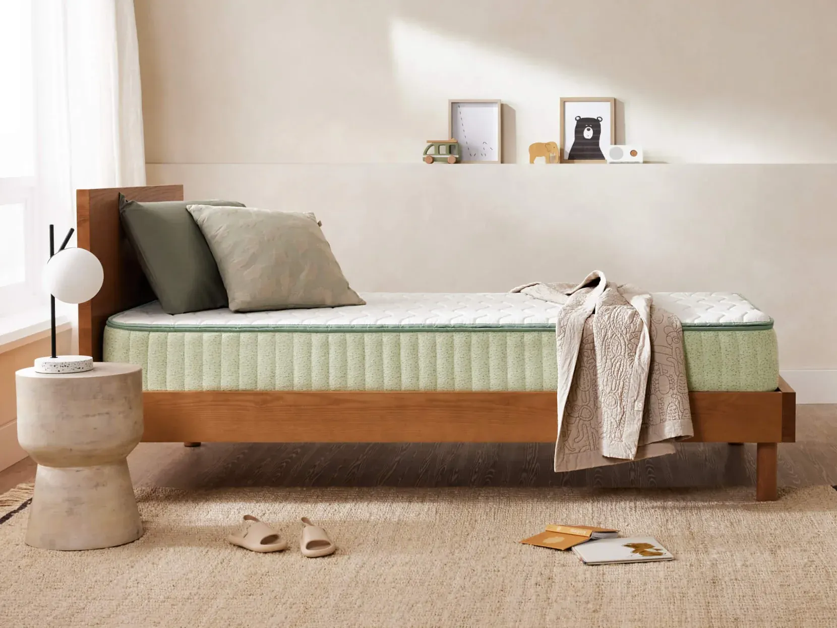 The Koala mattress on a timber single bed base in a child's room, showing the pale green quilted side and white top panel.