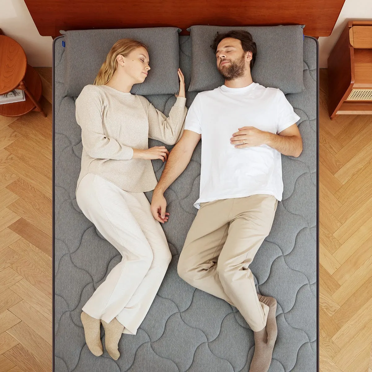 Overhead view of two people lying on the Newentor Hybrid mattress, showing the grey quilted cover across a double bed.