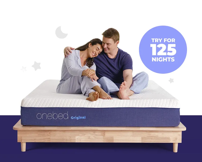 Two people sitting on the Onebed Original mattress beside a badge reading "Try for 125 nights".