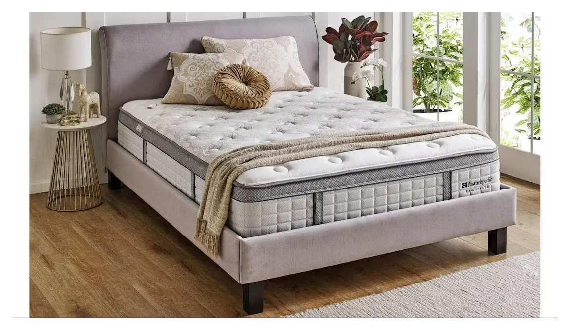 The Sealy Posturepedic Exquisite Rosewood on a grey upholstered bed base, showing its deep pillow-top and tufted surface.